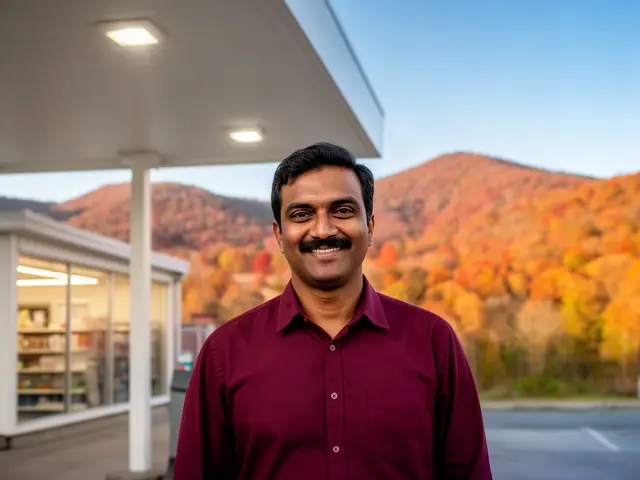 A smiling gas-station owner under the canopy with autumn ridges beyond.